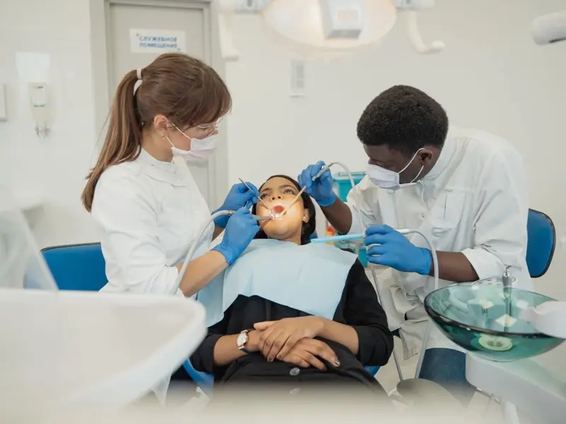 A dentist and assistant treating a patient in the clinic