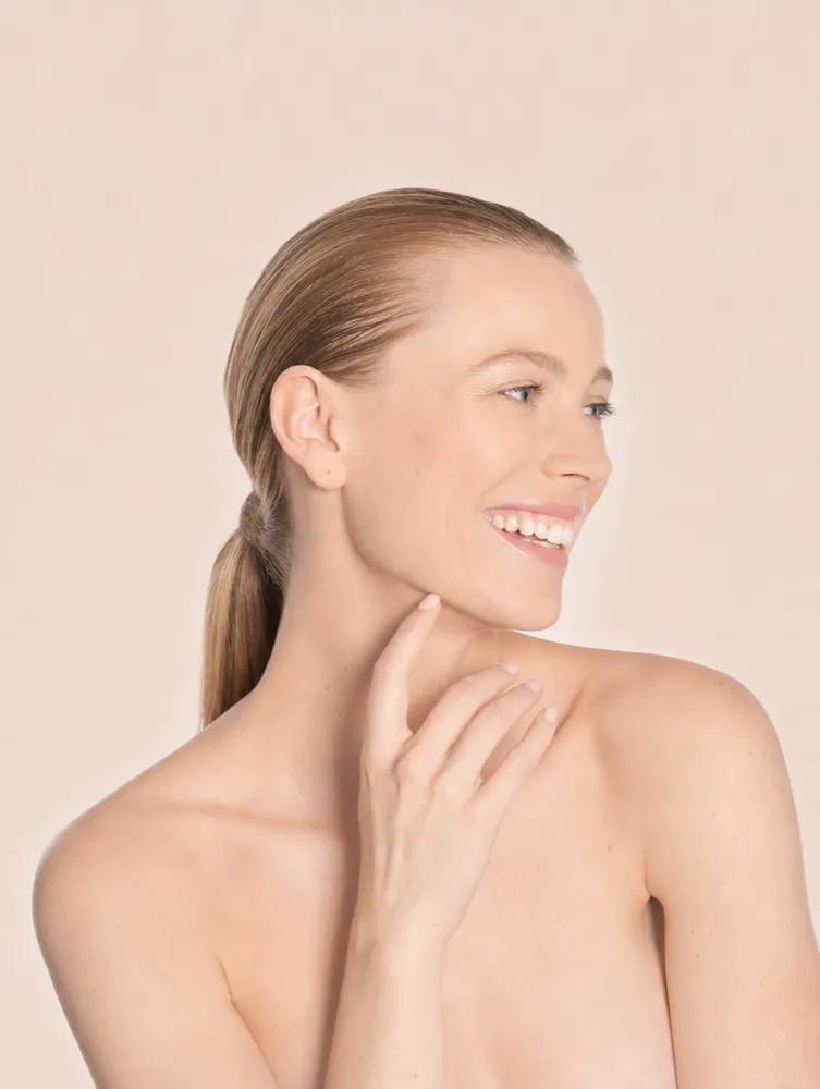 Profile of a woman smiling, one hand resting near her collarbone
