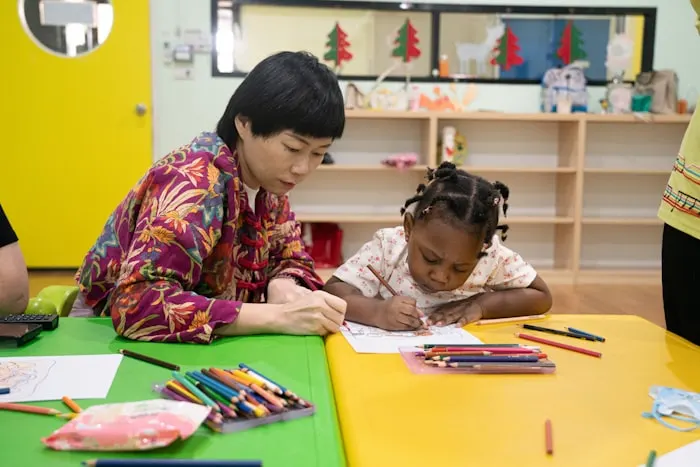 A teacher and a child drawing together at a table
