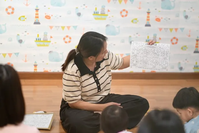 An early-childhood educator holding a learning worksheet in a classroom