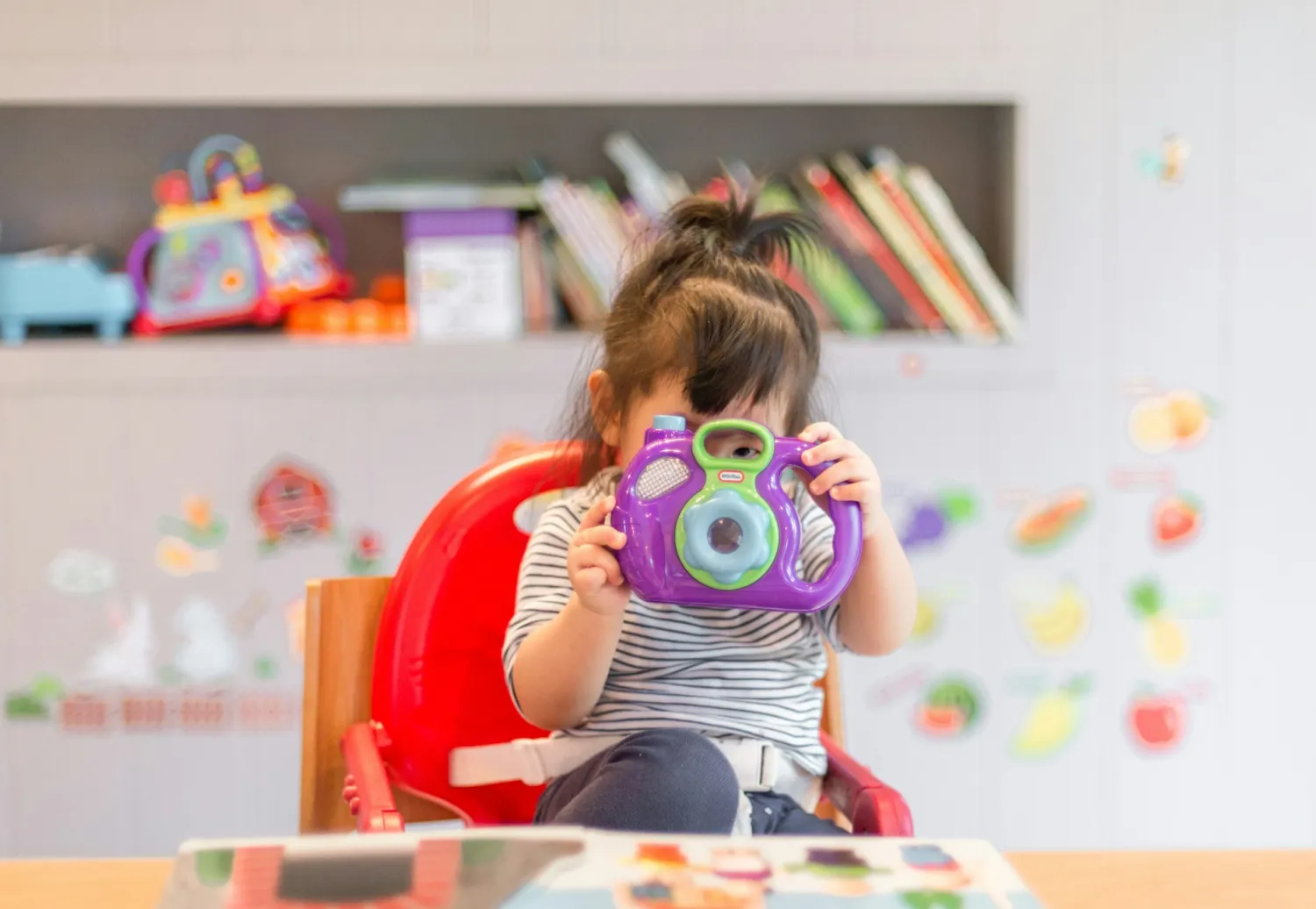 A child at the daycare holding a toy camera up to their face